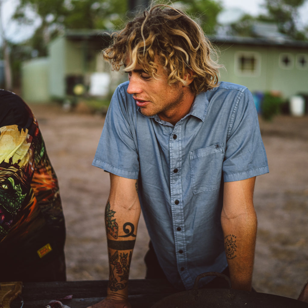 Man with tattoos wearing a blue shirt outdoors Big Image - 2