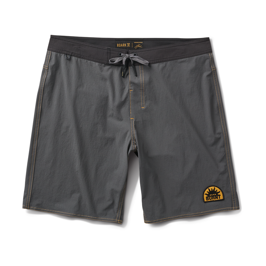 Roark boardshorts and surfboard set against a scenic surfing backdrop, symbolizing adventure and freedom in the great outdoors. Big Image - 1