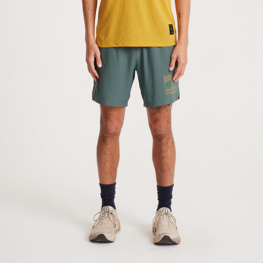 Male model wearing green running shorts with 'Open Roads Open Minds' graphic, paired with a mustard yellow T-shirt, front view. Big Image - 2