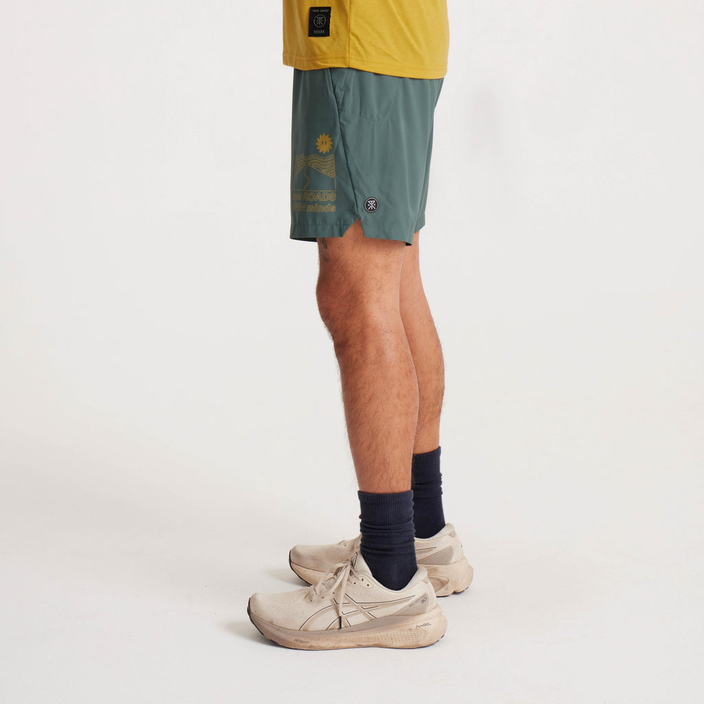 Back view of green running shorts with elastic waistband, modeled with a mustard yellow T-shirt. Big Image - 5