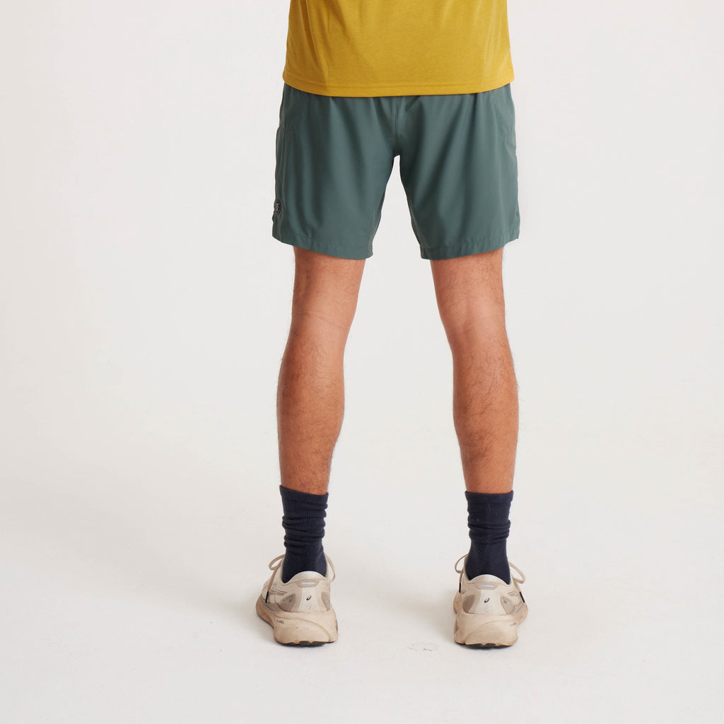 Detailed close-up of a model wearing green running shorts, highlighting the side zipper pocket and logo branding. Big Image - 6