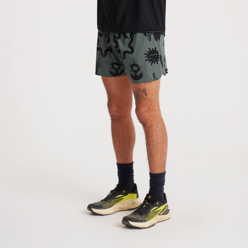 Side view of green graphic running shorts, paired with sneakers and styled for athletic and casual activities. Big Image - 3