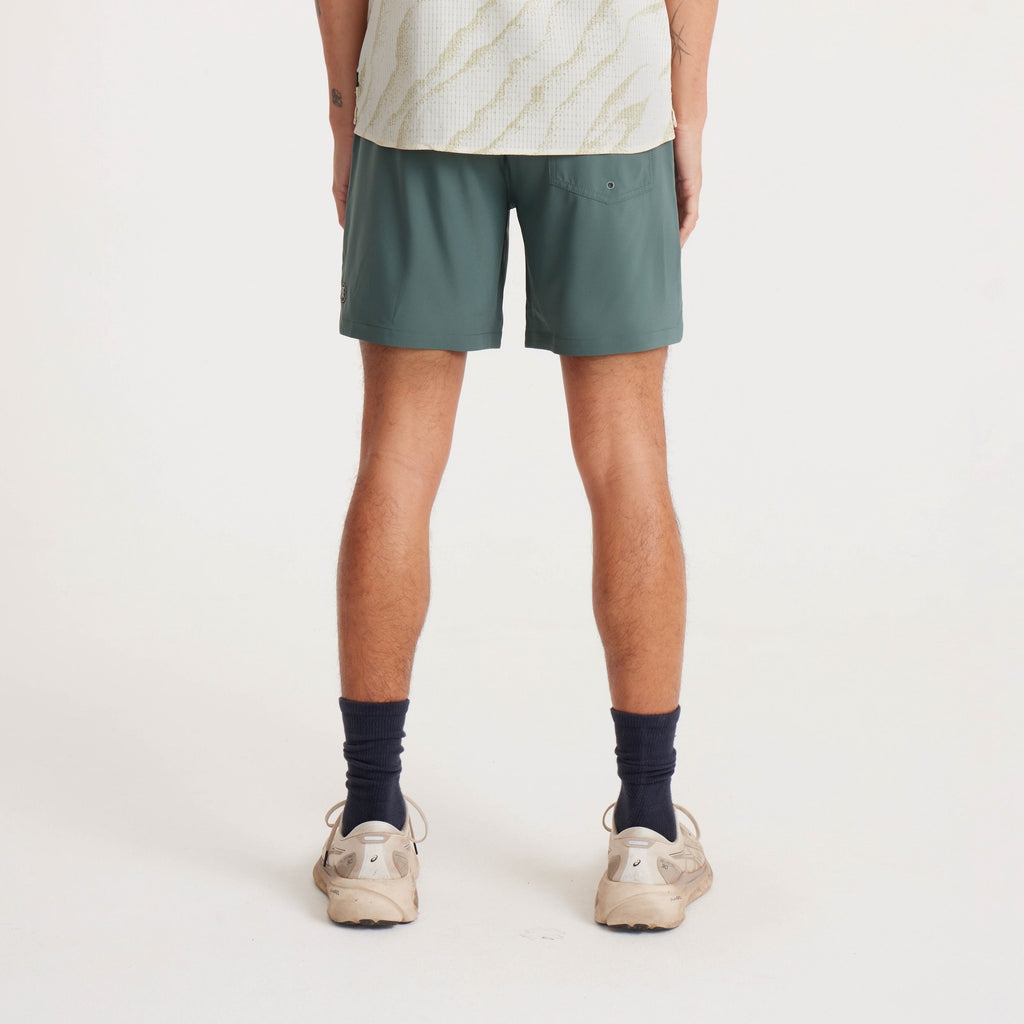 Rear view of green active shorts paired with neutral sneakers, designed for outdoor and athletic activities. Big Image - 4