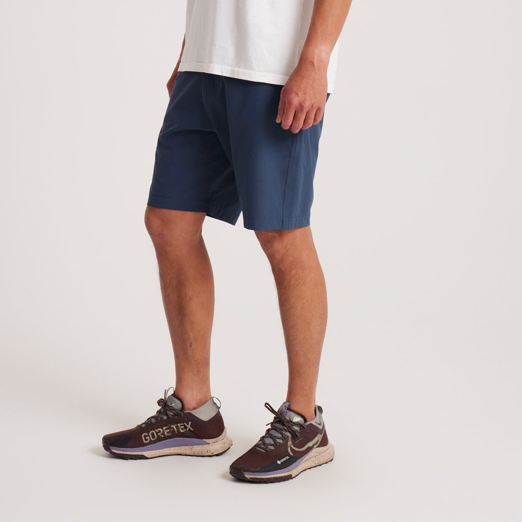 Side view of navy hybrid shorts on a model, displaying their tailored fit and functional pocket design. Big Image - 5