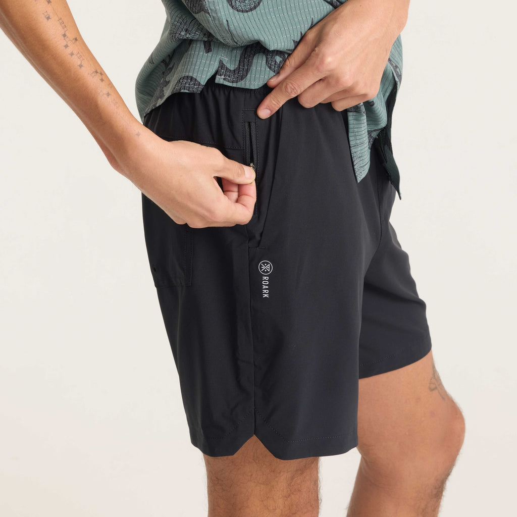 Model demonstrating the use of the side zip pocket on black Serrano shorts, highlighting secure storage and practical design. Big Image - 7