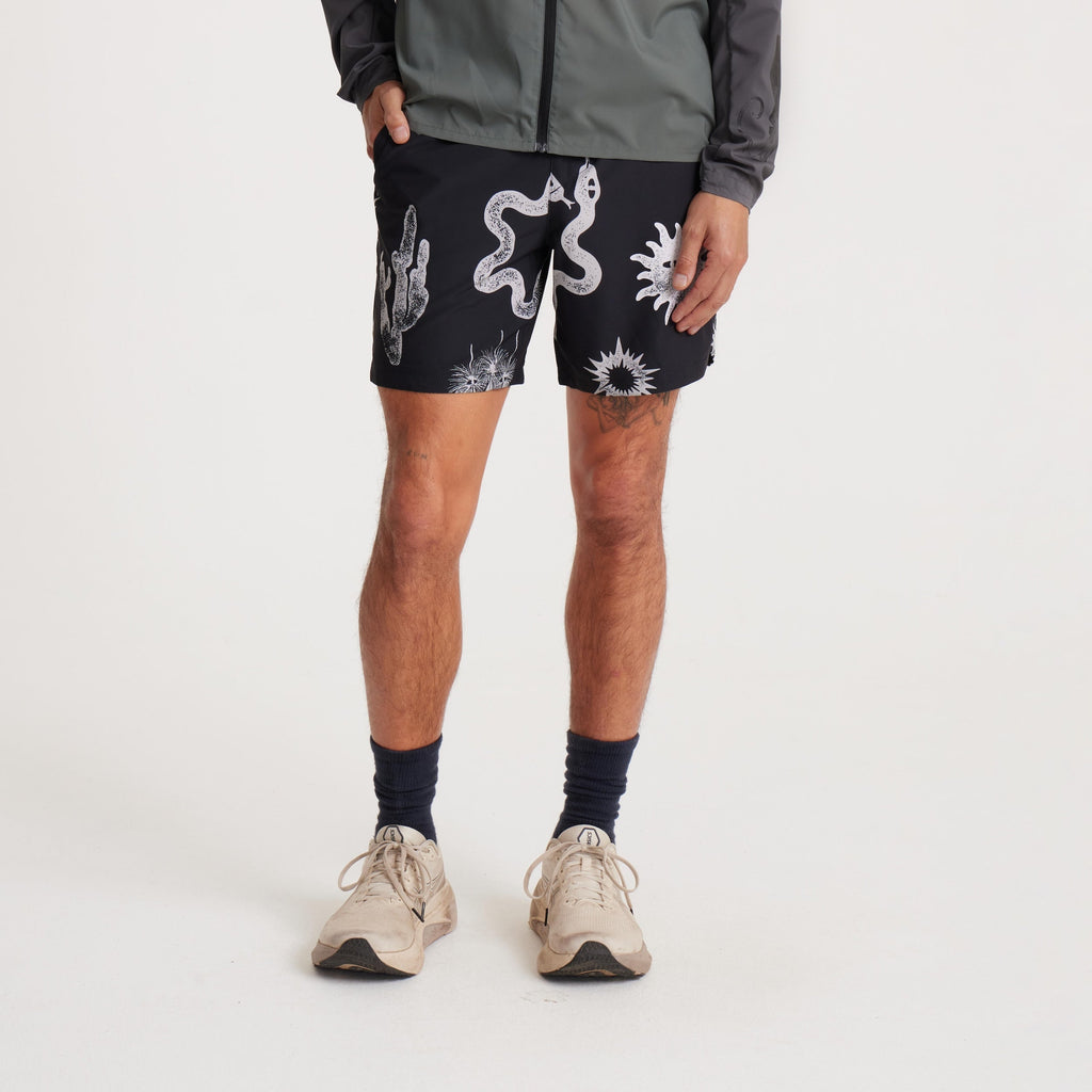 Front angled view of a model showcasing black swim shorts with bold white designs, including cacti and sun motifs, perfect for beach and outdoor adventures. Big Image - 3