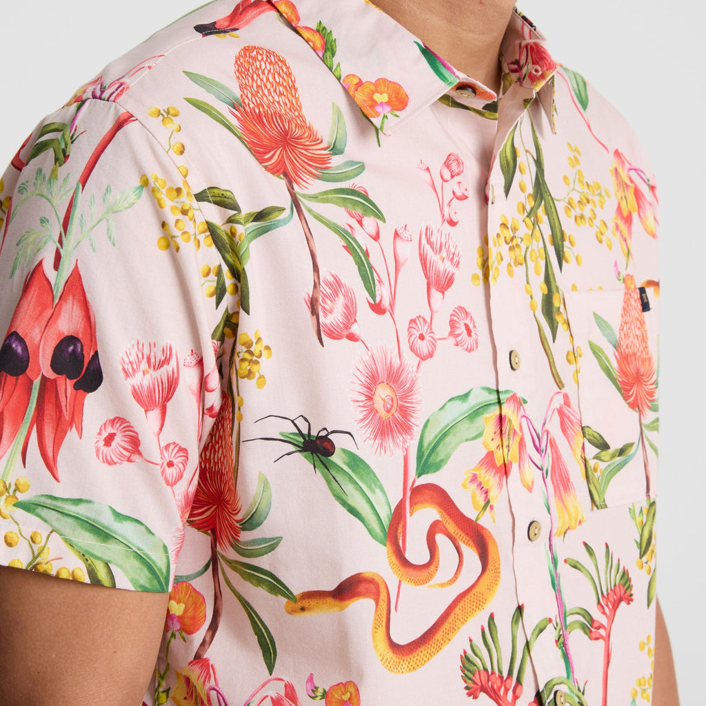 Person in a vibrant yellow active shirt admiring red geraniums, embodying Roark's spirit of outdoor adventure and travel. Big Image - 12