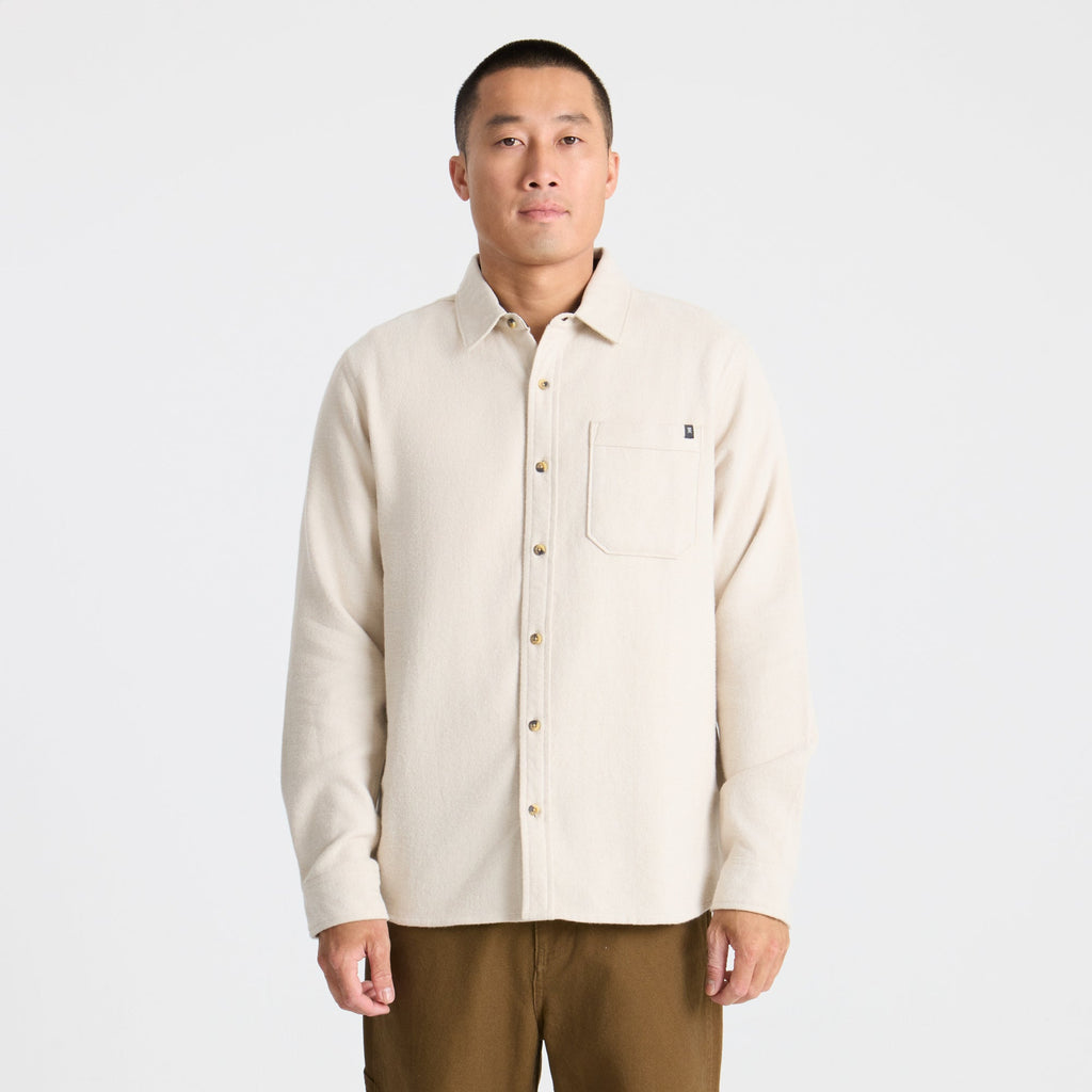 Man in Roark RW665 adventure gear standing on a forested summit overlooking a valley at sunset, embodying the spirit of exploration and travel. Big Image - 2