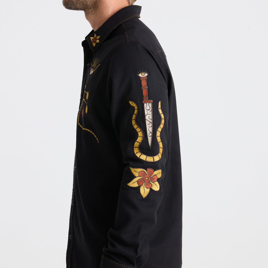 Close-up of a black Roark active denim shirt featuring detailed stitching on the collar and sleeve with visible buttons, perfect for outdoor adventures. Big Image - 7