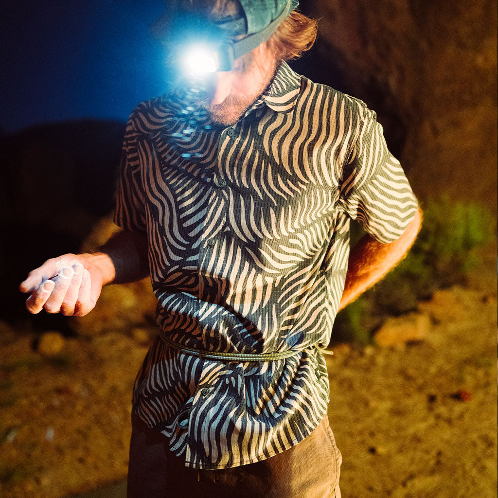 Person wearing a zebra-patterned shirt with a flashlight on a dark background Big Image - 2