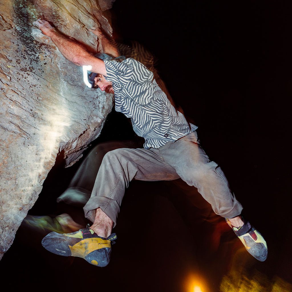 Person rock climbing in a dark cave with artificial lighting. Big Image - 2