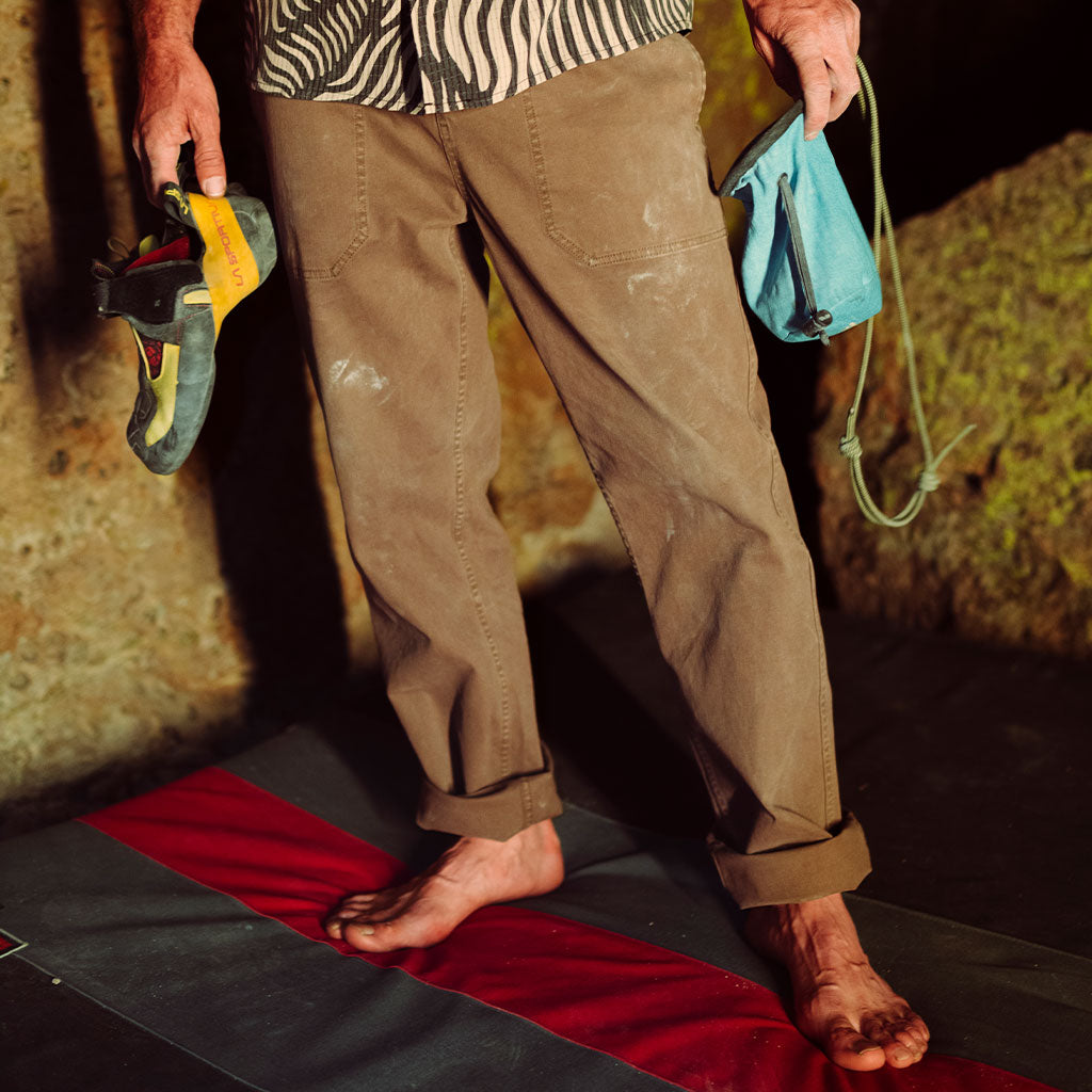 Person wearing brown pants with climbing equipment on a red and black mat. Big Image - 2