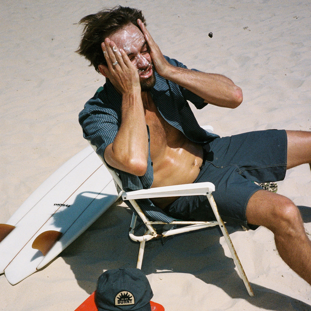 sun smart man on the beach applying sunscreen just like mama used to do it Big Image - 2